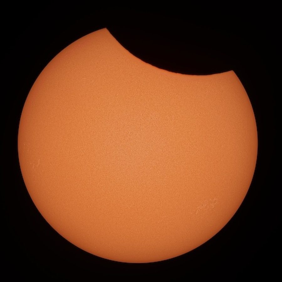 Eine fesselnde gelb-orangene Ansicht einer Sonnenfinsternis mit einer hellen Halbmondform am dunklen Himmel.