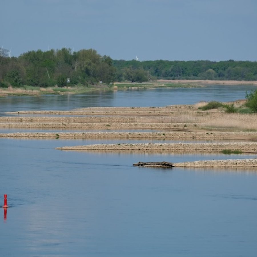 Niedrigwasser in einem Flussbett mit freigelegten Kiesbänken im Sommer