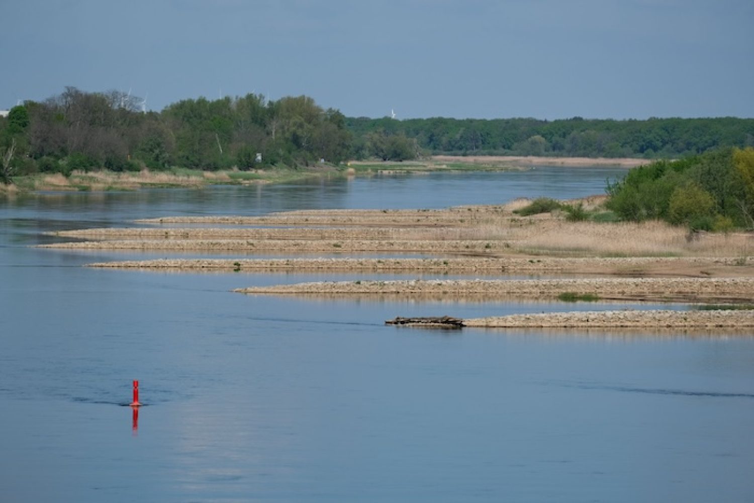 Niedrigwasser in einem Flussbett mit freigelegten Kiesbänken im Sommer