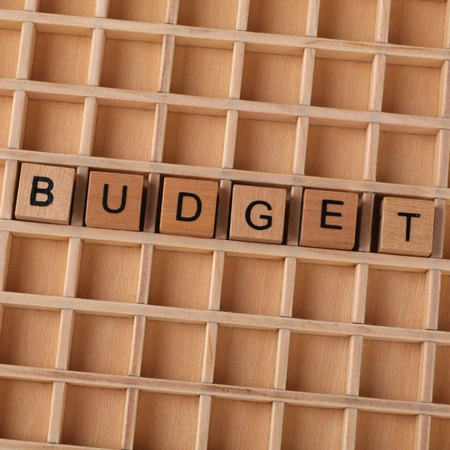 Schriftzug "Budget" bestehend aus einzelnen Buchstaben auf kleinen quadratischen Holzklötzen in einem Holzsetzkasten, als Symbolbild für die Kürzung von Eventbudgets