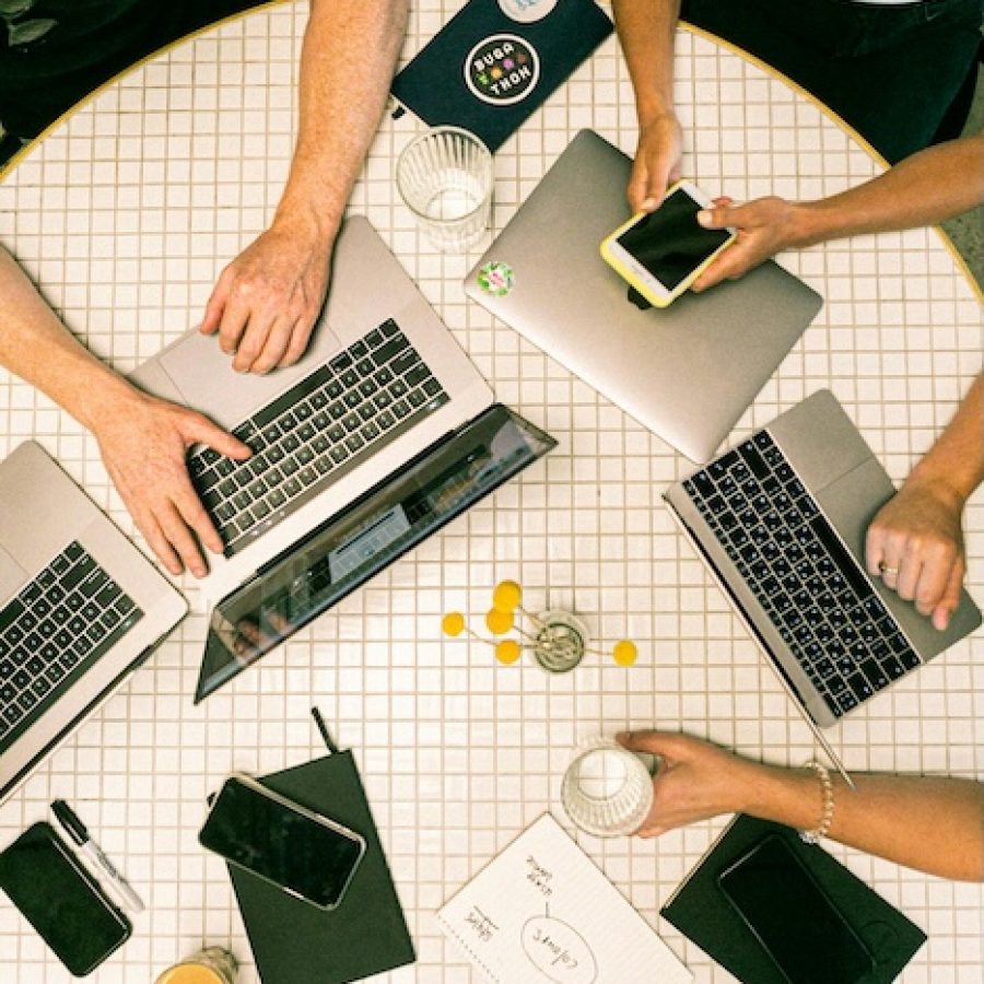Eventplanung auf rundem Tisch mit diversen Laptops