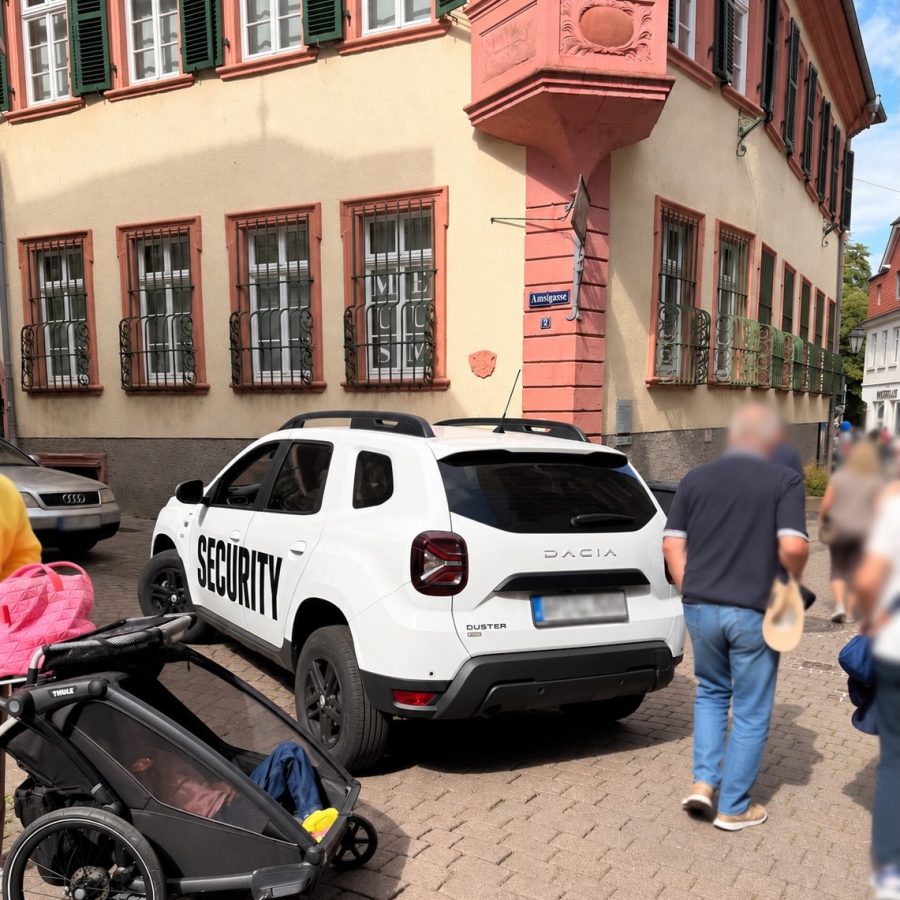 Weißes Fahrzeug mit Aufschrift Security blockiert beim Weinheimer Herbst eine Zufahrt in der Innenstadt, daneben gehen Passanten vorbei