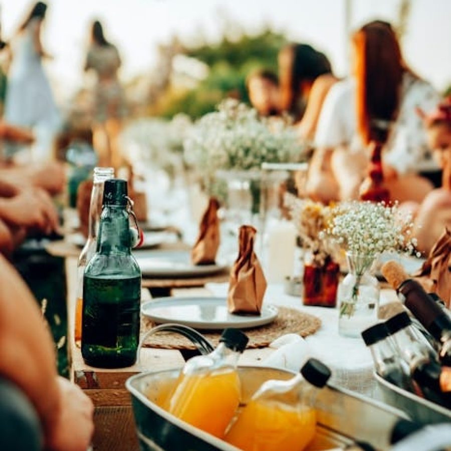 Feierende Mitarbeiterinnen und Mitarbeiter bei einen firmeninternen Sommerparty am gut eingedeckten Gartentisch