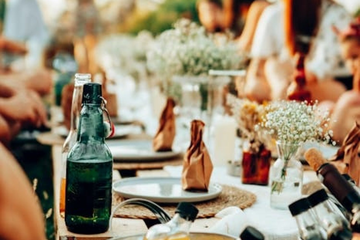 Feierende Mitarbeiterinnen und Mitarbeiter bei einen firmeninternen Sommerparty am gut eingedeckten Gartentisch