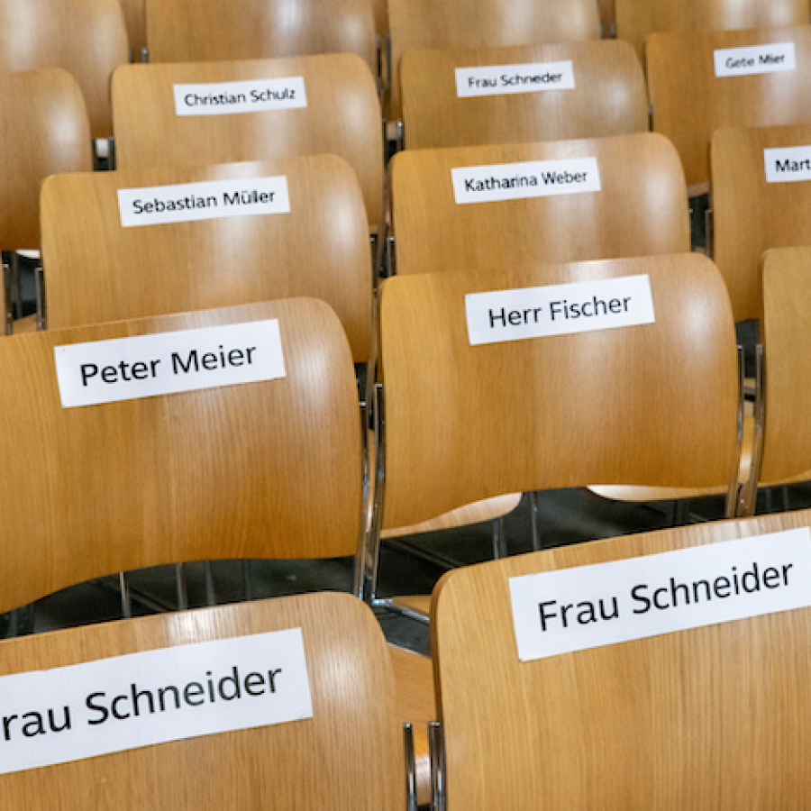 Stuhlreihen mit aufgeklebten Namensschildern